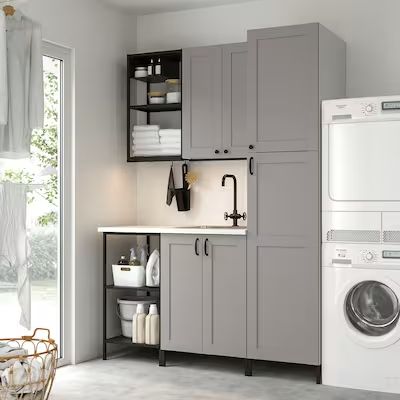 a washer, dryer and cabinets in a room with a door open to the outside