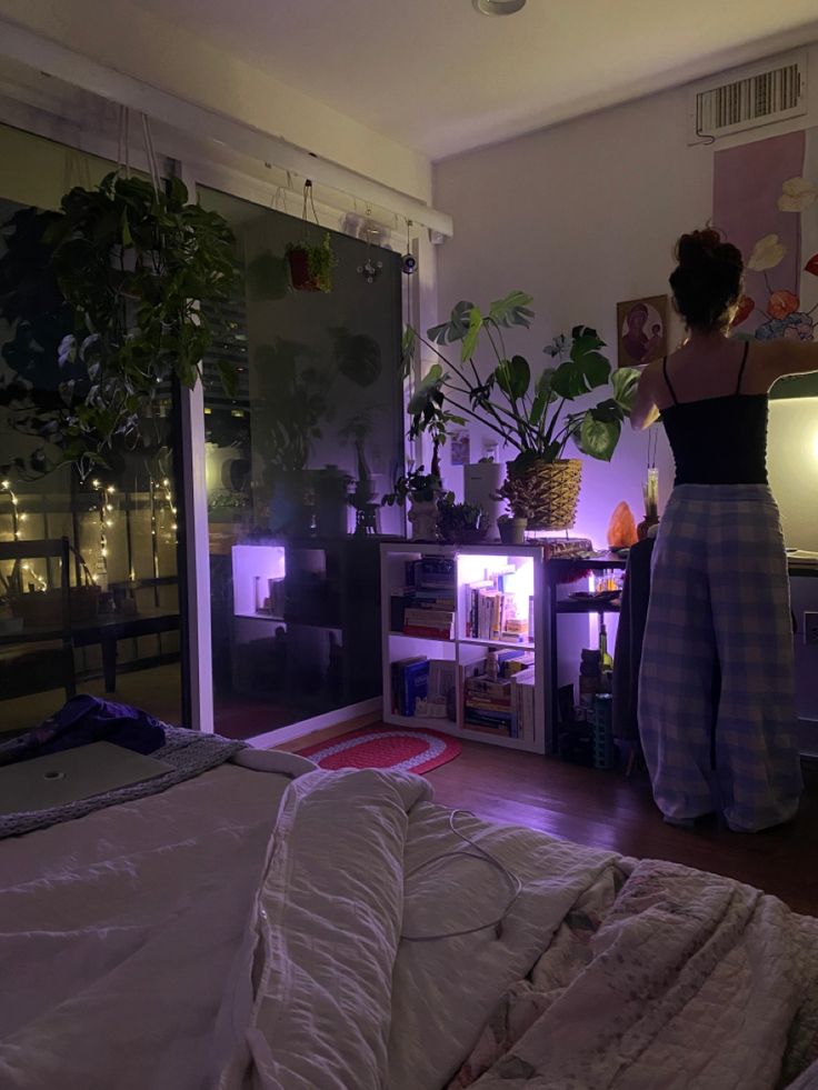 a woman standing in front of a tv next to a bed