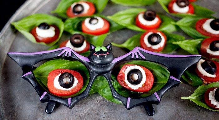 a plate topped with lots of fake eyes and bats on top of leafy green leaves