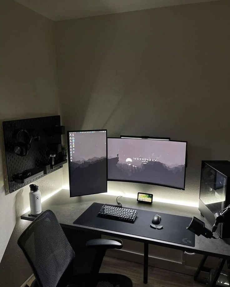 a computer desk with two monitors and a keyboard on it in front of a wall