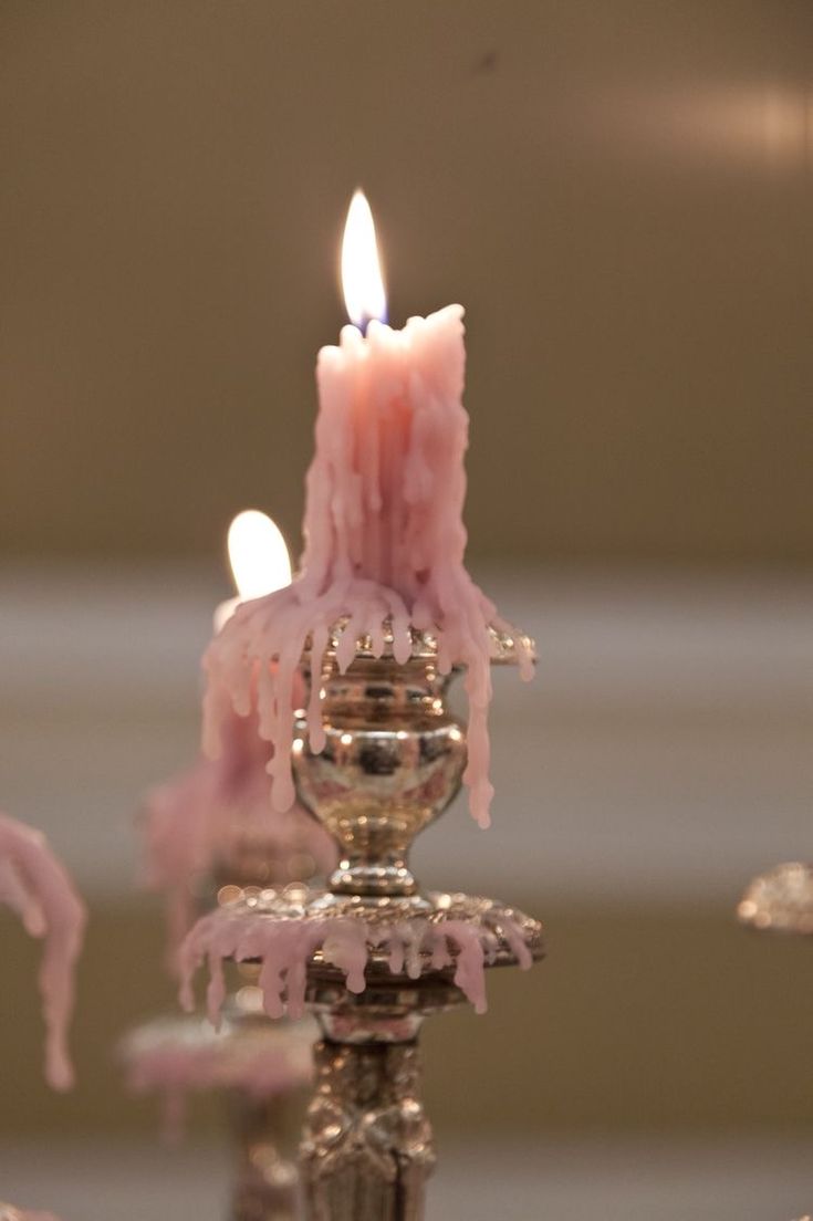 a candle that is sitting on top of a metal stand with pink icing around it