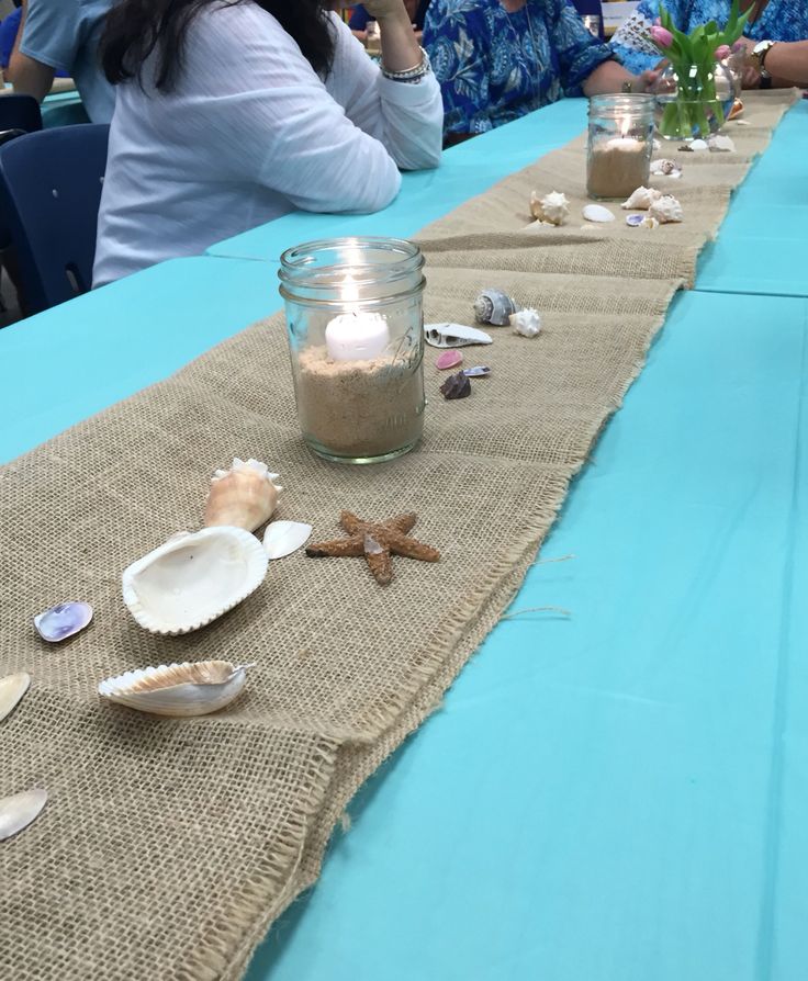 people sitting at a table with candles and seashells