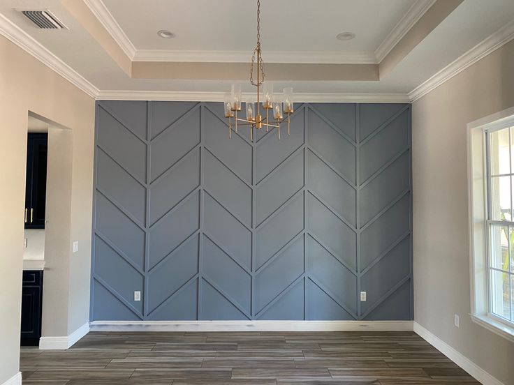 an empty room with wood flooring and blue wall art on the walls, along with a chandelier