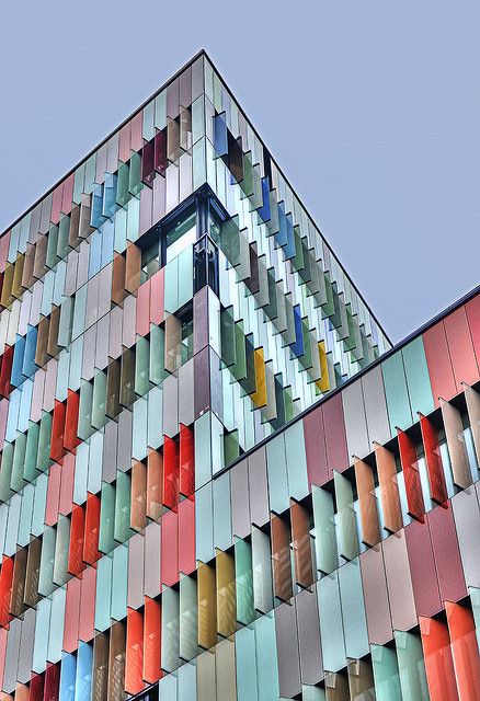 the side of a multi - colored building that has many windows on it and is very tall