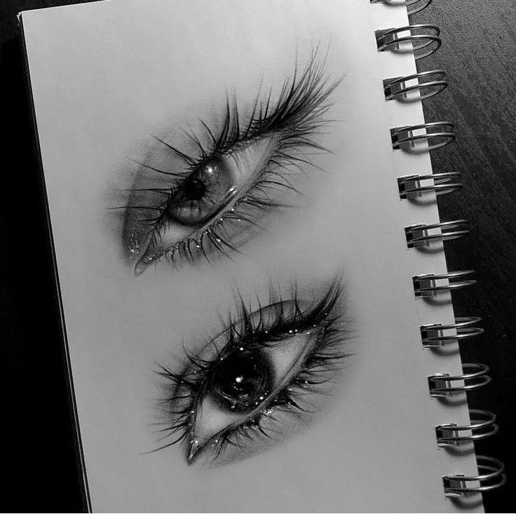 an open spiral notebook with drawings of eyes and lashes on top of each other,