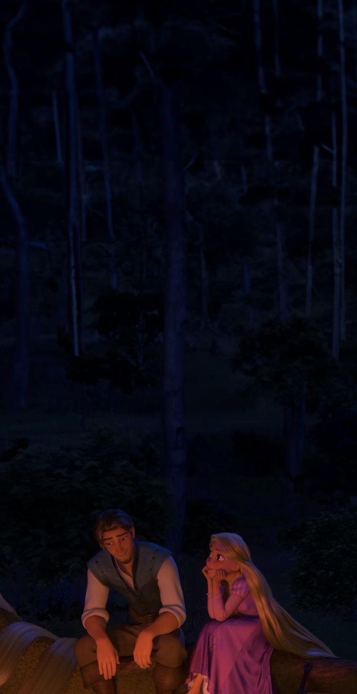 a man and woman sitting next to each other in front of a campfire at night