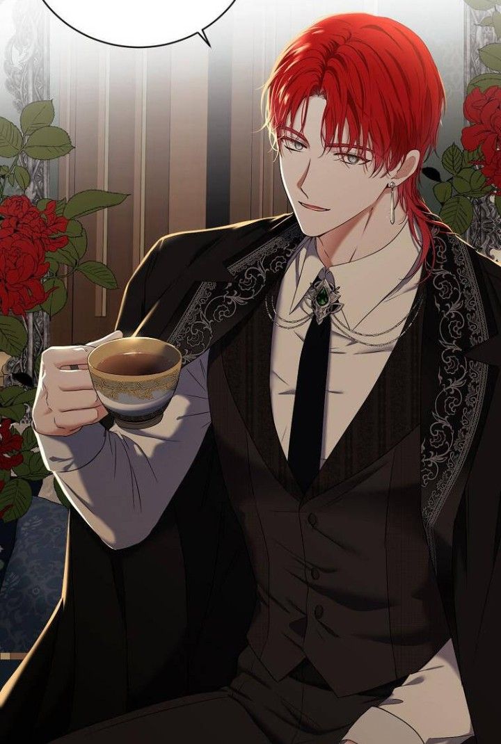 a man with red hair sitting down holding a cup in his hand and looking at the camera