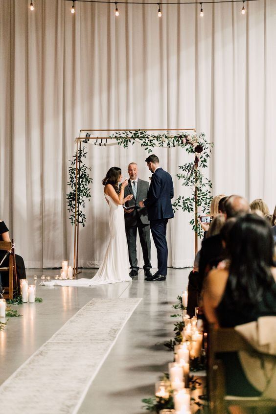 a bride and groom standing at the end of their wedding ceremony with candles in front of them