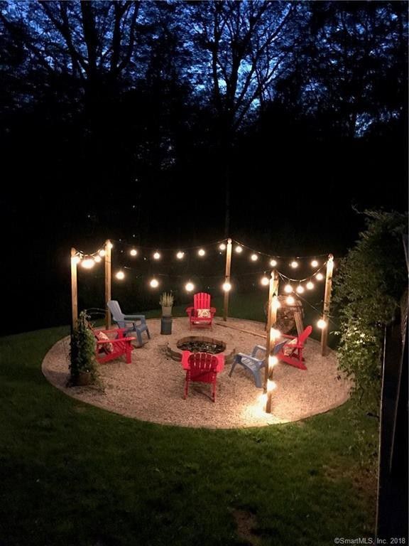 a fire pit surrounded by lawn chairs and string lights