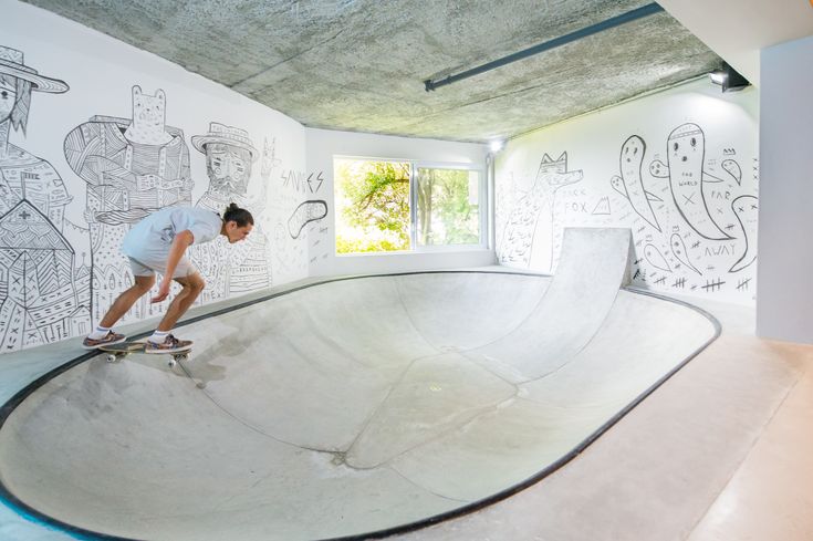 a man riding a skateboard up the side of a ramp in a room filled with drawings