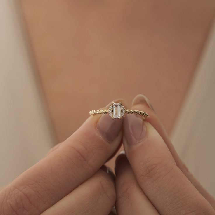 a close up of a person's hand holding a ring with a diamond on it