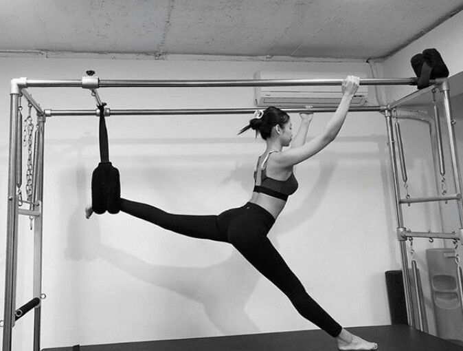 a woman is doing an acrobatic exercise on a bar with one leg in the air