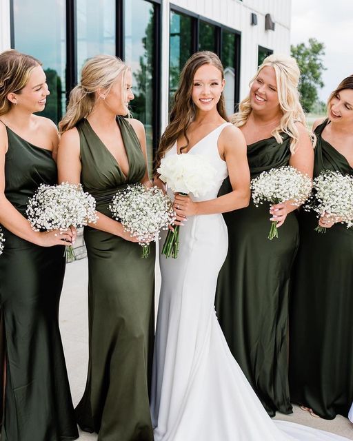 a group of women standing next to each other in front of a building holding bouquets