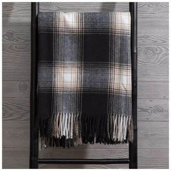 the black and white plaid blanket is hanging on a chair in front of a wooden wall