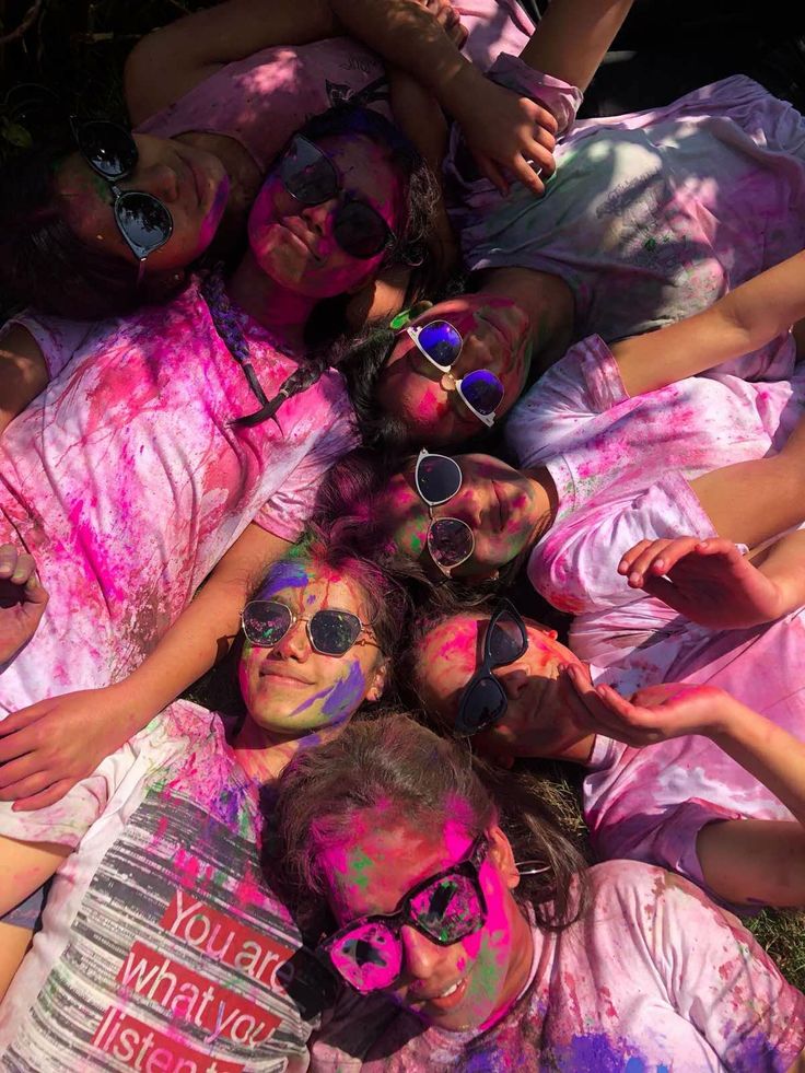 group of people covered in pink and blue paint laying on the ground with their arms around each other