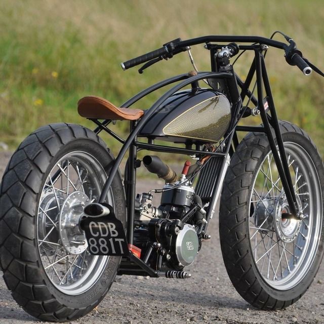 a small motorcycle parked on the side of a road next to a grass covered field