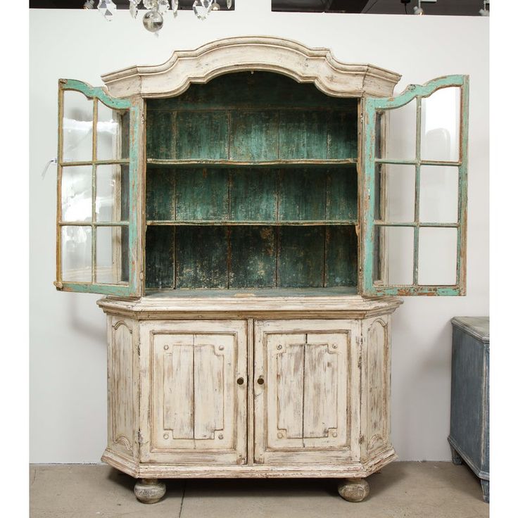 an old white china cabinet with glass doors and drawers on the front, sitting against a wall