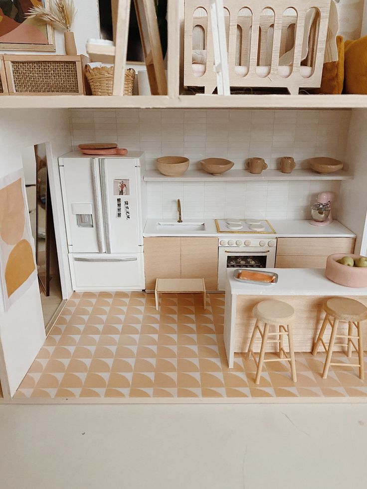 a doll house kitchen with white appliances and wooden shelves on the wall, including a refrigerator