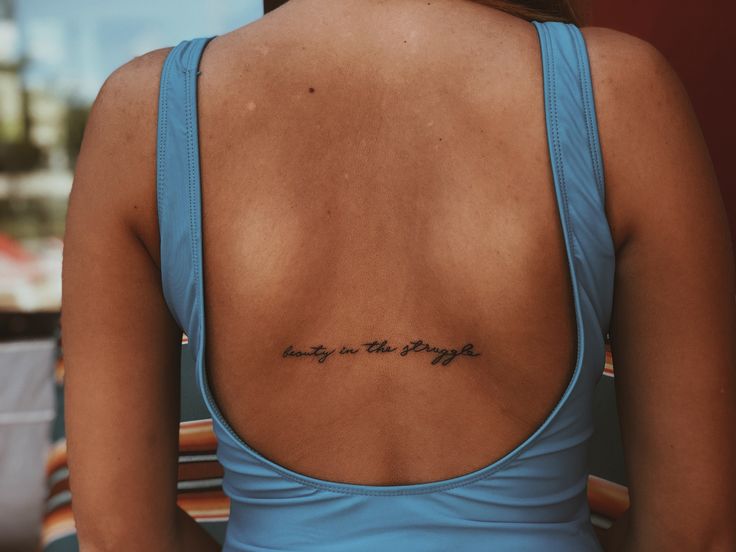 the back of a woman's blue tank top with writing on her left side