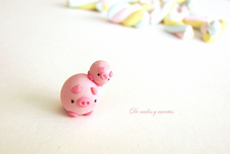 two small pink pig figurines sitting next to each other on a white surface