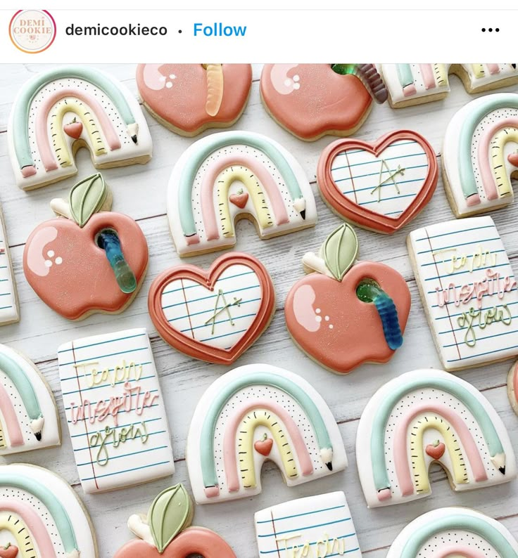 decorated cookies with rainbows, apples, and hearts are arranged on a white table