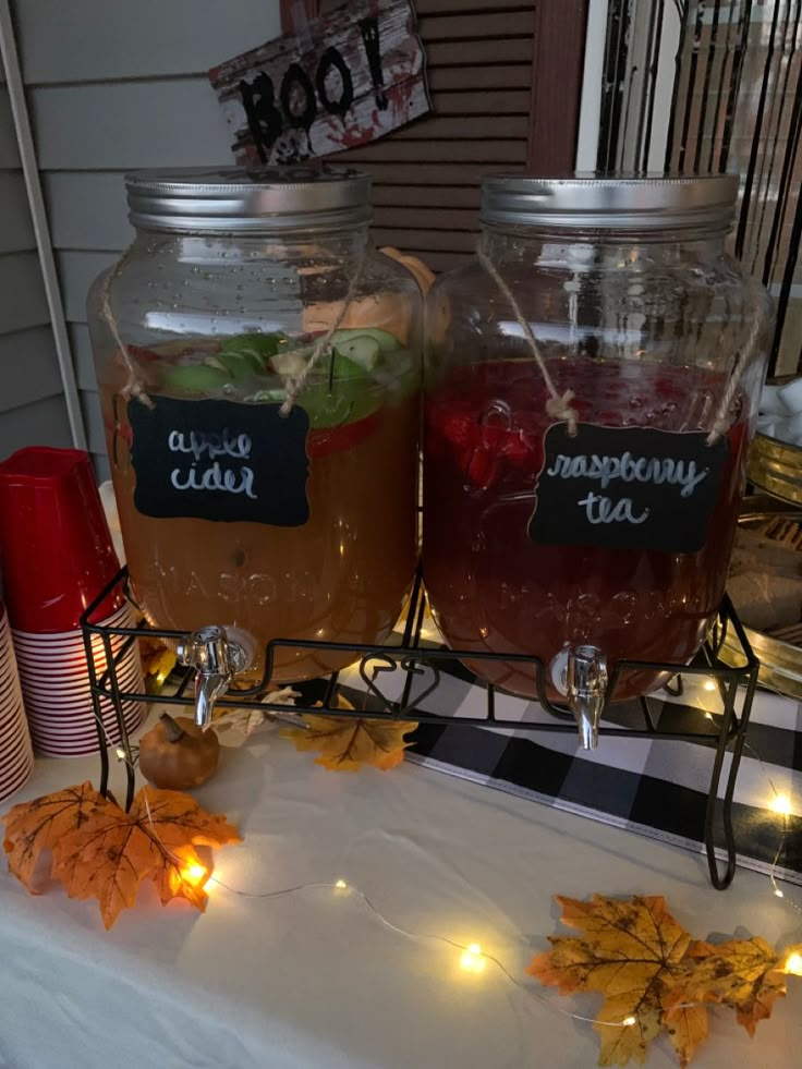 two mason jars filled with liquid sitting on top of a table covered in fall leaves