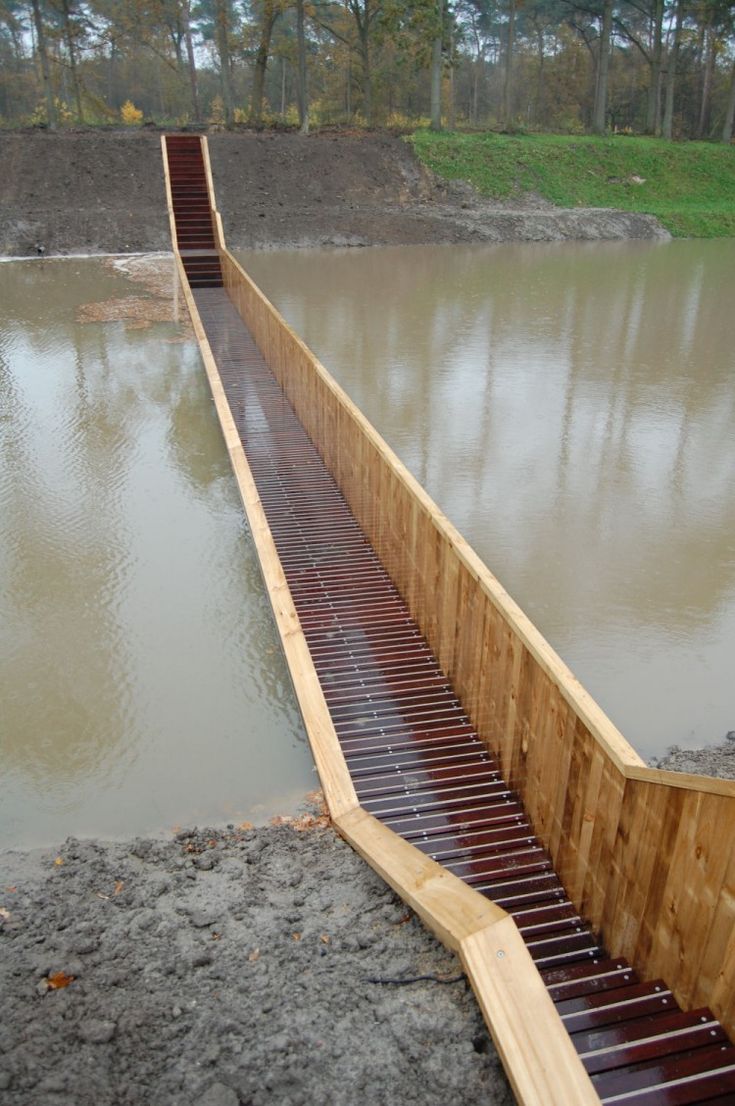 a wooden ramp over water in the middle of a field