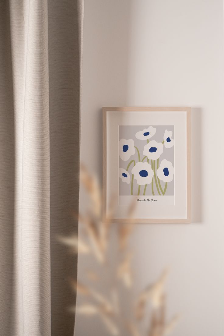 an art print hangs on the wall next to a window with drapes in it