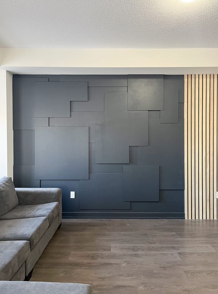 an empty living room with blue walls and wood flooring in the center, along with two gray couches