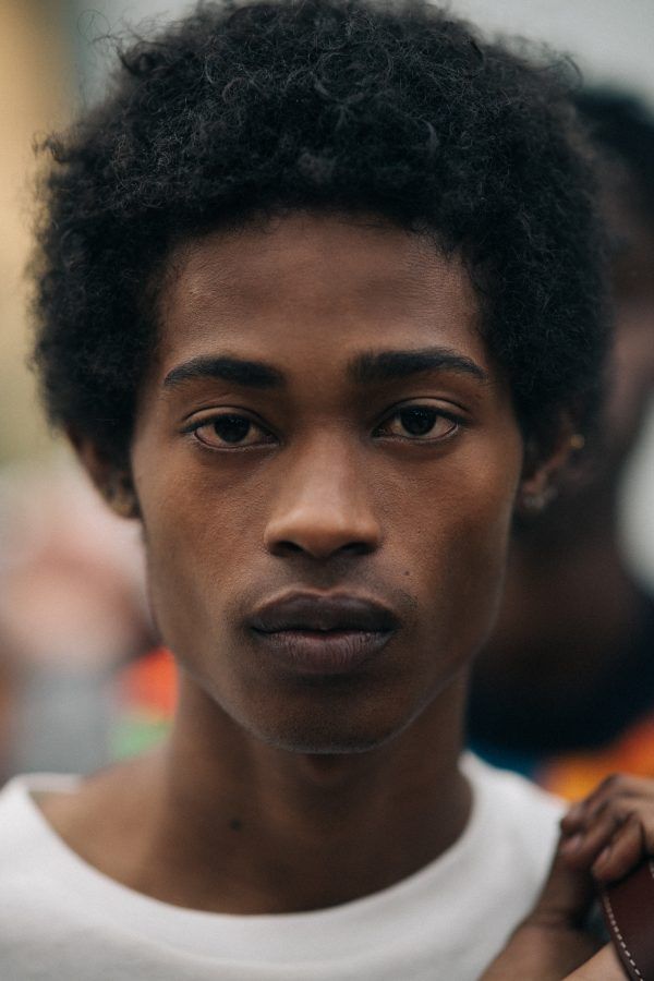 a close up of a person wearing a white t - shirt and holding a brown bag