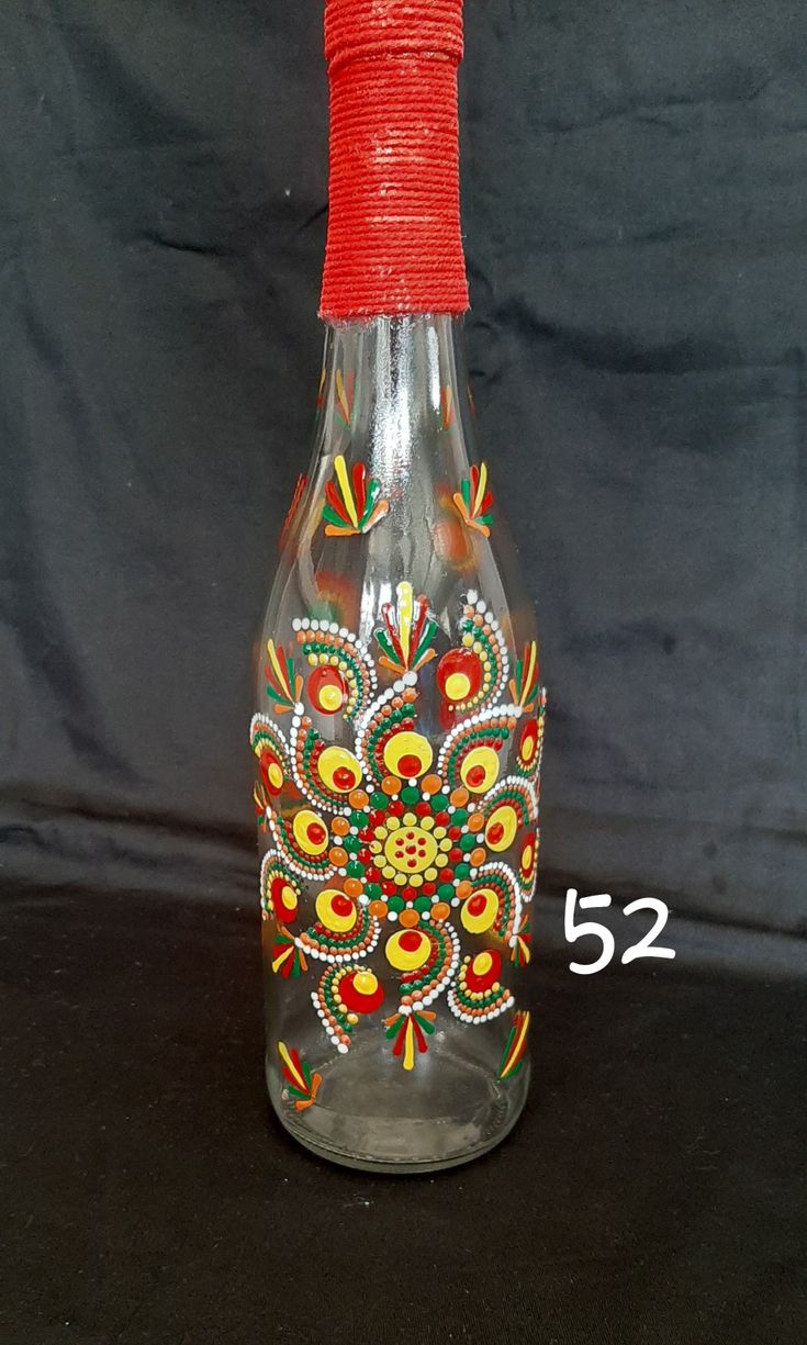 a glass bottle with an intricate design on the side and red string wrapped around it