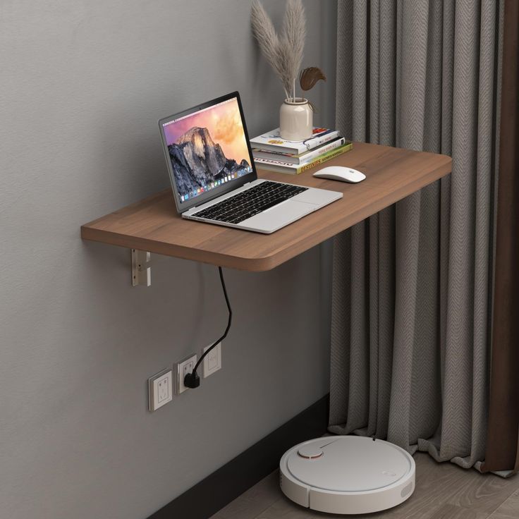 a laptop computer sitting on top of a wooden desk next to a wall mounted speaker