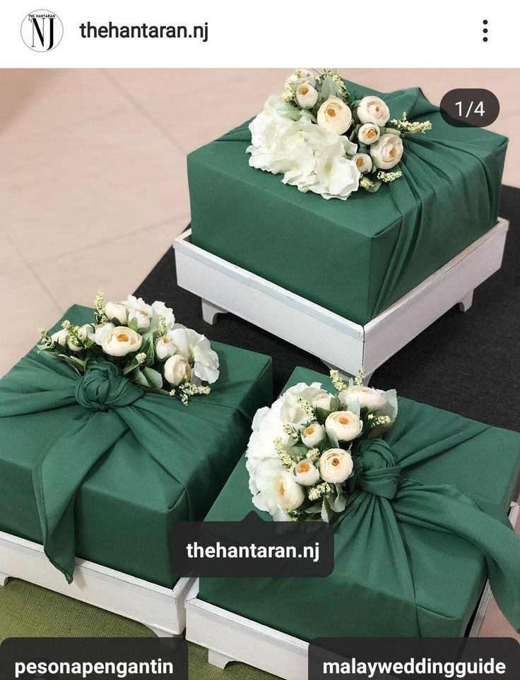 three green boxes with white flowers tied to them and labeled in the same language on each