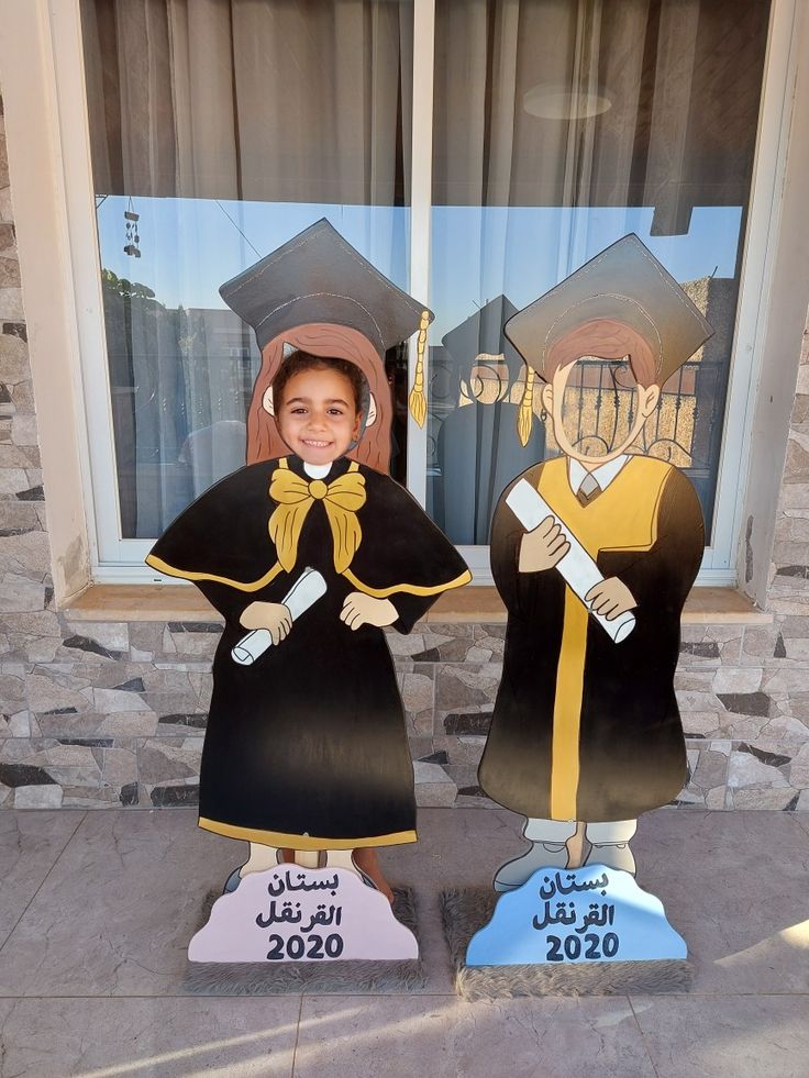 two children in graduation gowns standing next to each other with their diplomas on