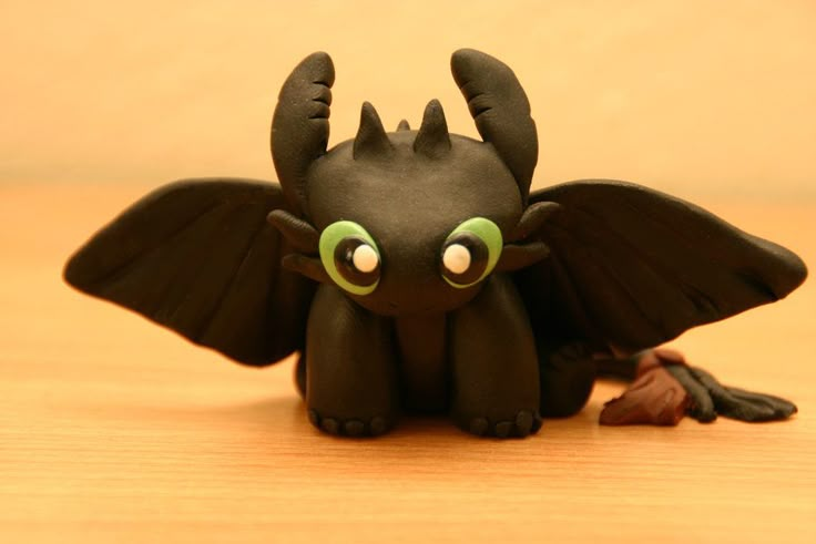 a black toy with green eyes sitting on top of a wooden table