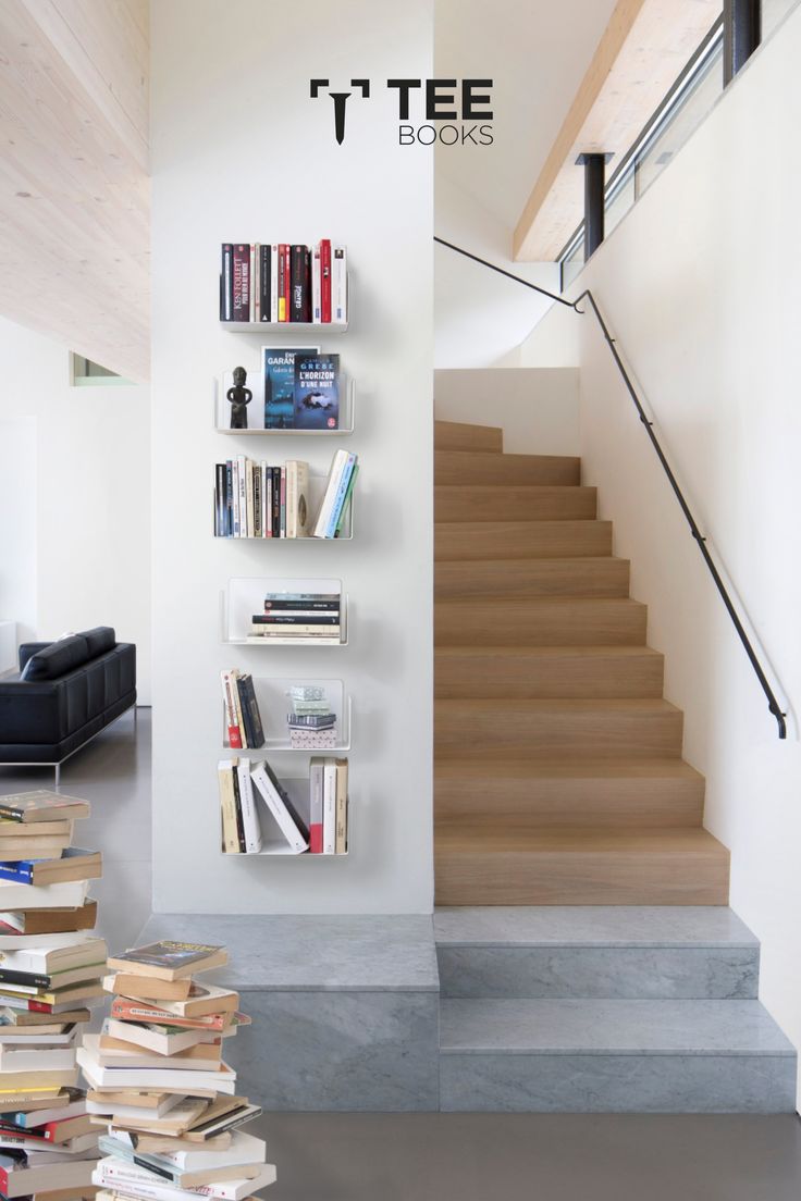 there is a book shelf with many books on it and stairs leading up to the second floor