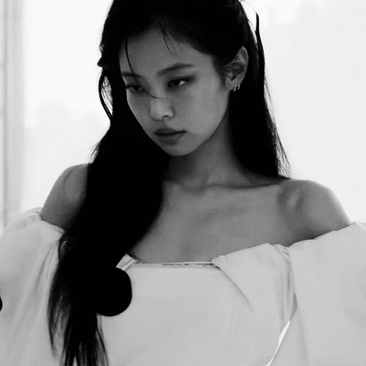 a black and white photo of a woman with long hair wearing a off the shoulder top