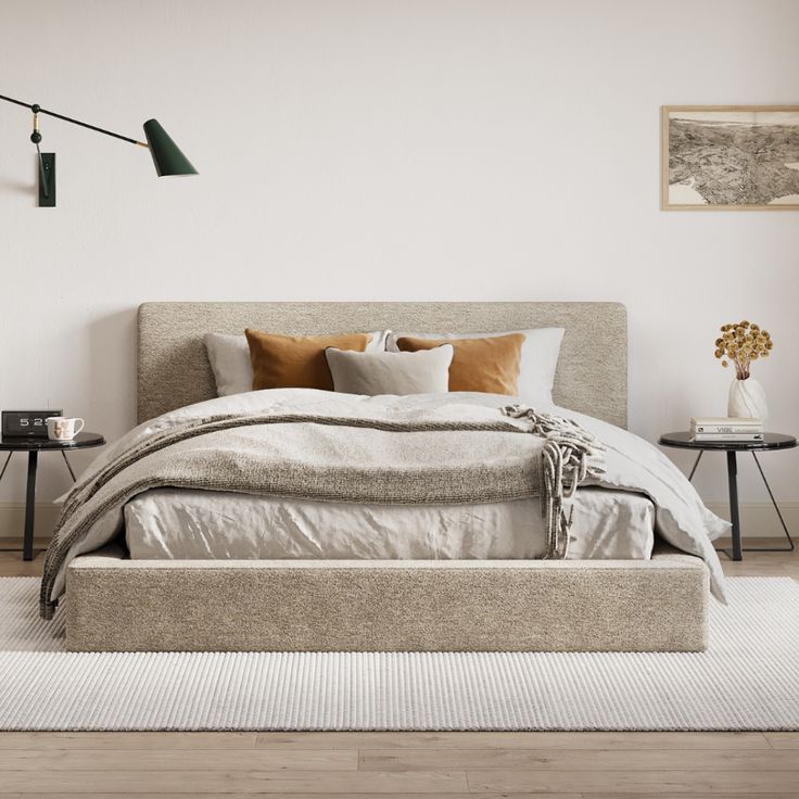 a large bed sitting on top of a wooden floor next to a wall mounted lamp