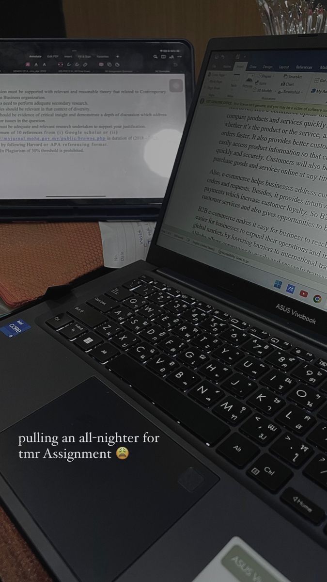 an open laptop computer sitting on top of a wooden desk next to another laptop computer