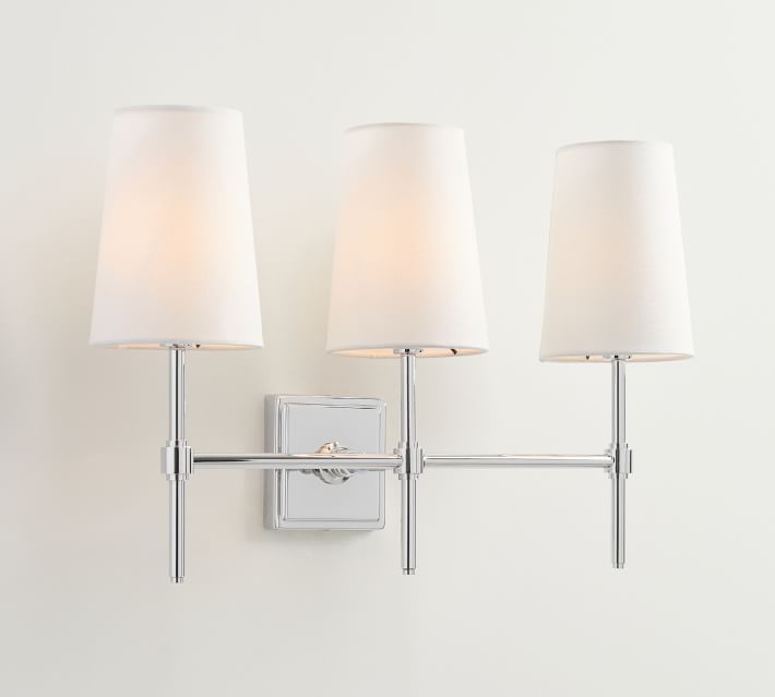 three lamps mounted on a wall next to a white light fixture with a square shaped shade