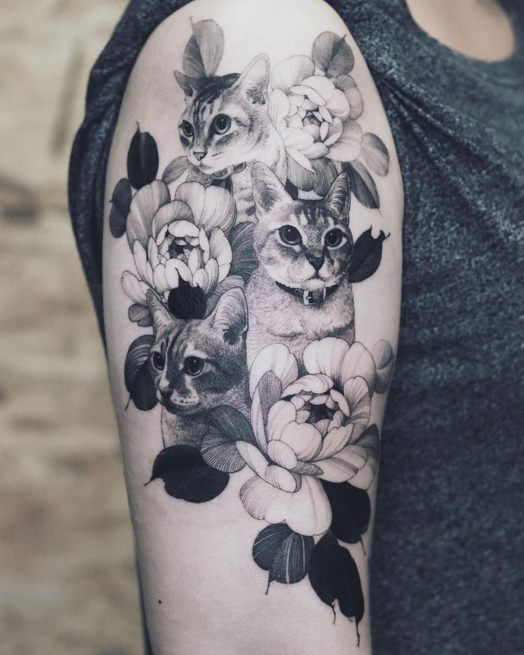 a woman's arm with flowers and cats on it