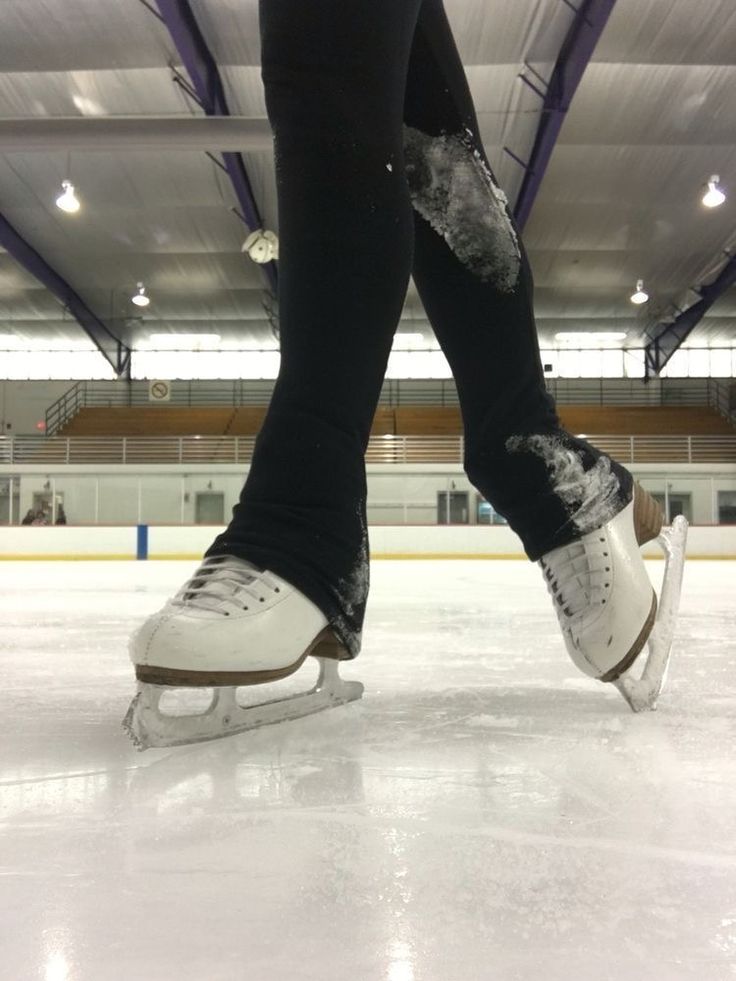 the legs and feet of a person skating on an ice rink