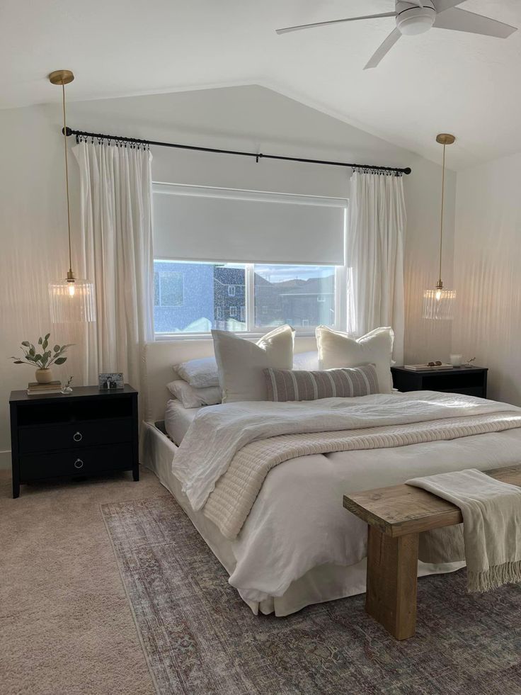 a large white bed sitting in a bedroom next to a window