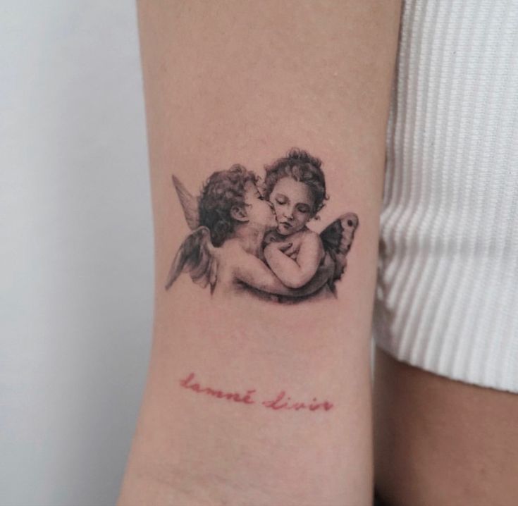 a small tattoo on the arm of a woman with an angel and a baby in her arms