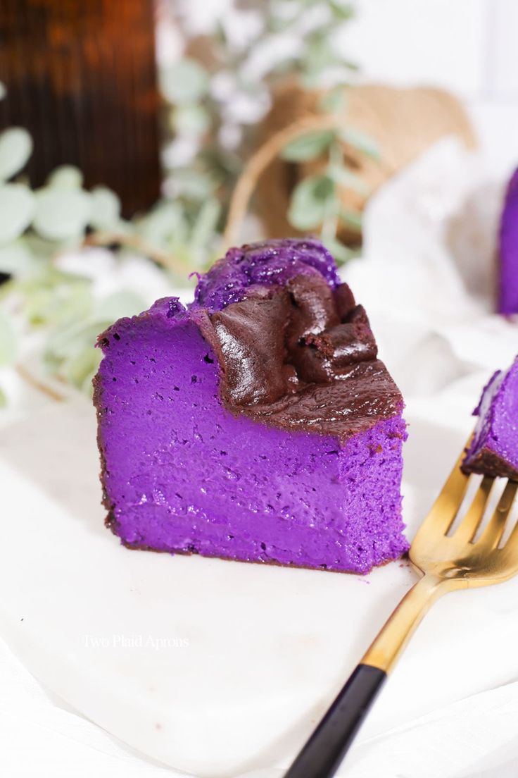 a piece of purple cake sitting on top of a white plate next to a fork