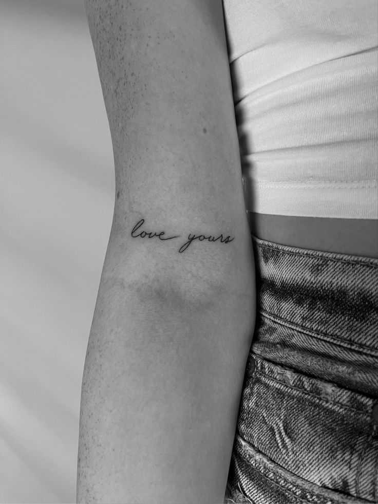 a woman's arm with the word love you tattooed on her left arm, in black and white