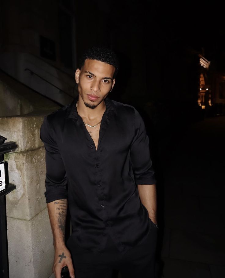 a man standing next to a mailbox in the dark with his hand on his hip