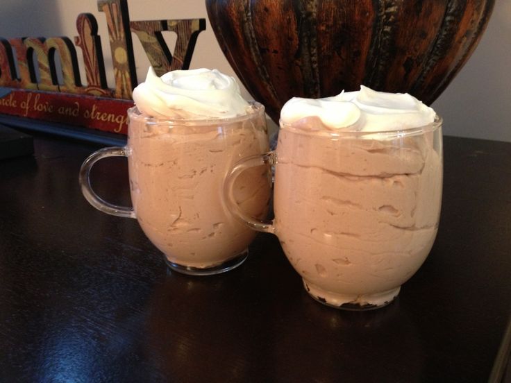 two glasses filled with whipped cream sitting on top of a table