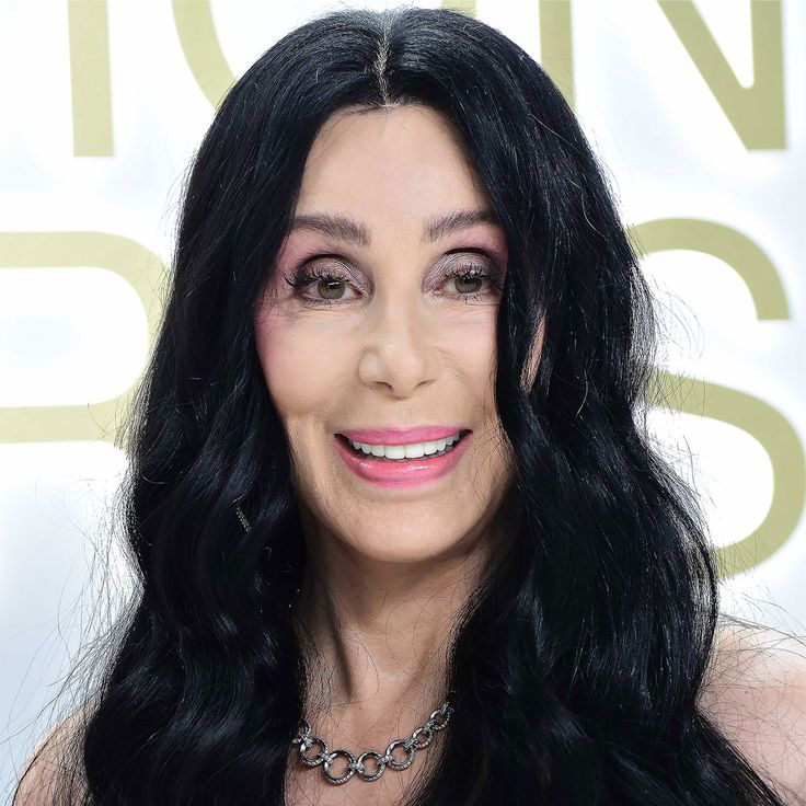 a woman with long black hair wearing a necklace and choker smiling at the camera