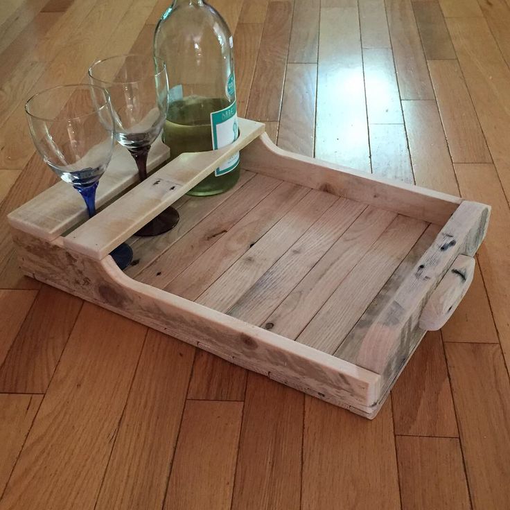 a wooden tray with three wine glasses and a decanter on it sitting on the floor